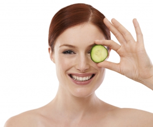 Cropped shot of a beautiful young woman holding a slice of cucumber against a white background